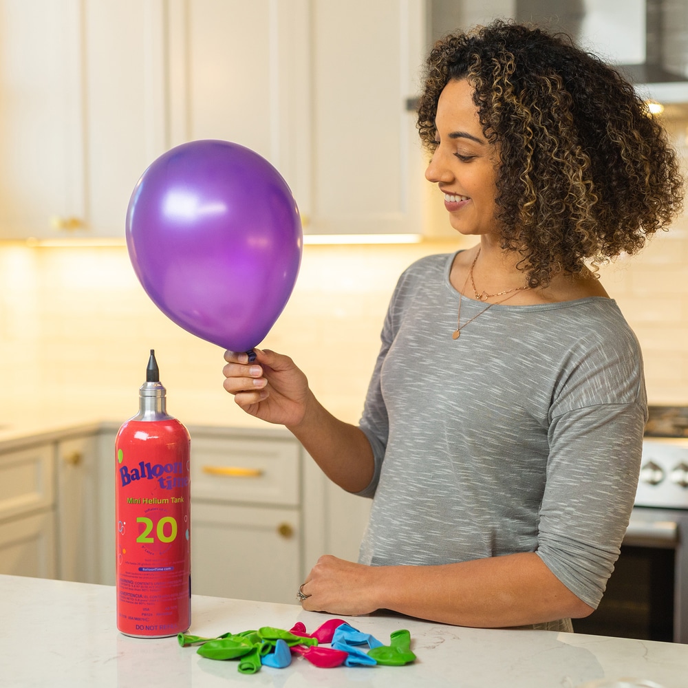 Woman holding filled balloon beside Mini Tank